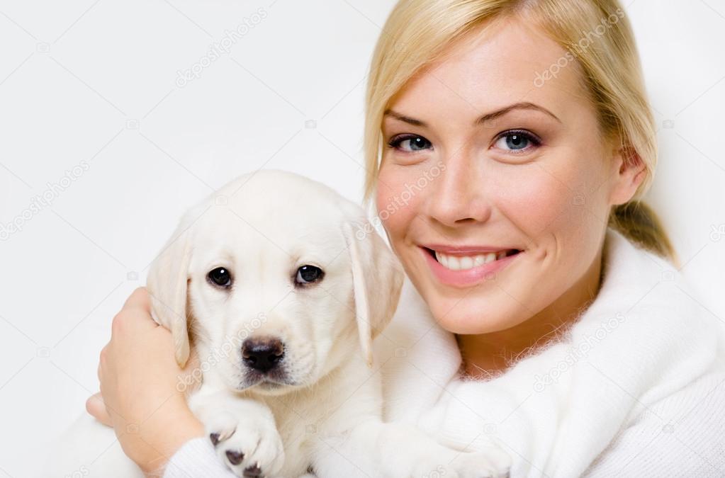 Labrador puppy sitting on the hands of woman