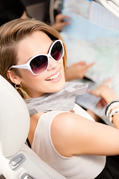 Chica con el mapa de carreteras en el coche — Foto de Stock