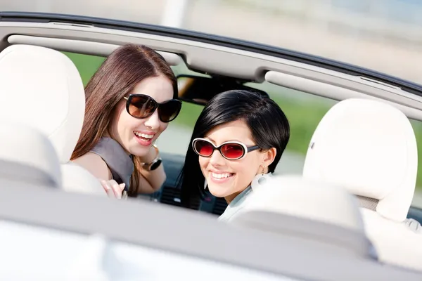 Zwei glückliche Mädchen, die im Auto sitzen, blicken zurück — Stockfoto