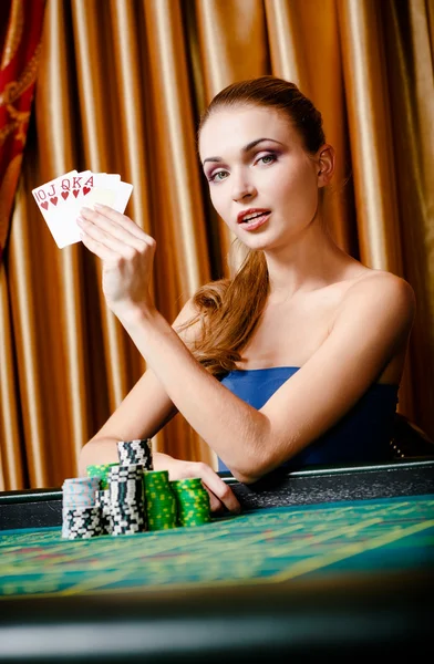 Vrouwelijke gokker aan de pokertafel met kaarten en chips — Stockfoto