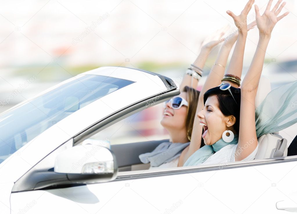 Female friends in the cabriolet with hands up