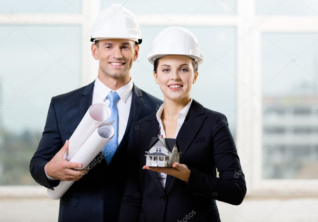 Two contractors keeping blueprints and model house