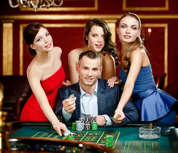 Man surrounded by girls gambles roulette — Stock Photo, Image