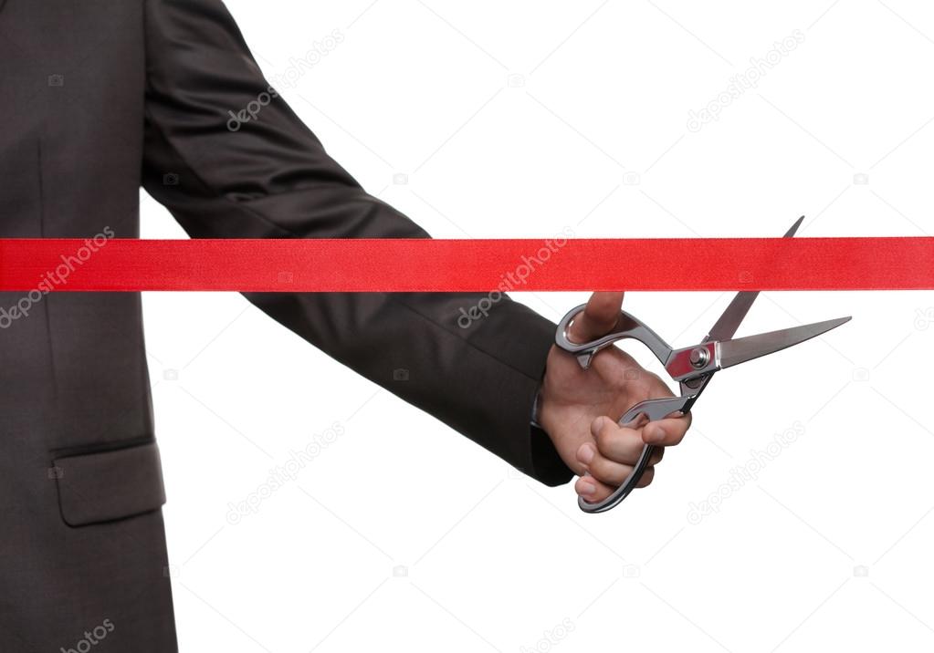 A businessman cutting a scarlet ribbon