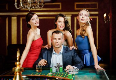 güzel kızlar tarafından çevrili adam Ruleti oynuyor