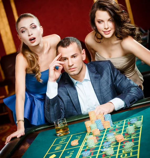 Mann mit zwei Mädchen beim Roulette im Casino — Stockfoto