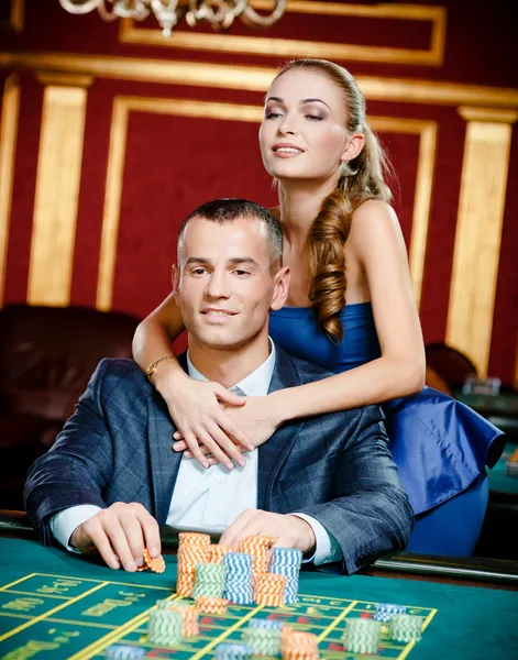 Ragazza abbracciando giocatore d'azzardo al tavolo da gioco — Foto Stock