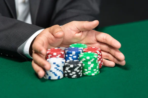 Giocatore che va "all in" spingendo le sue fiches di poker in avanti Foto Stock Royalty Free