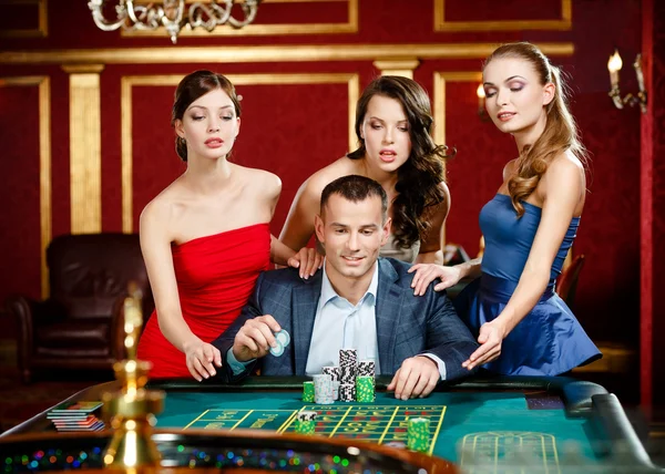 Man surrounded by pretty girls gambles roulette Stock Photo