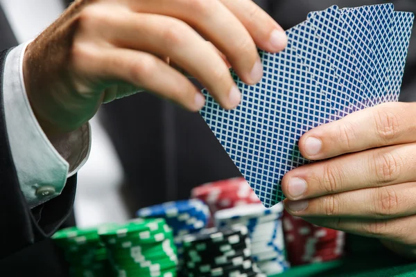 Jugador jugando a las cartas de poker con fichas de poker en la mesa de poker — Foto de Stock