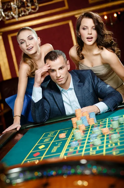 Hombre con dos mujeres jugando ruleta en el casino — Foto de Stock