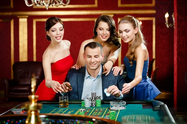 Man omringd door vrouwen speelt roulette — Stockfoto