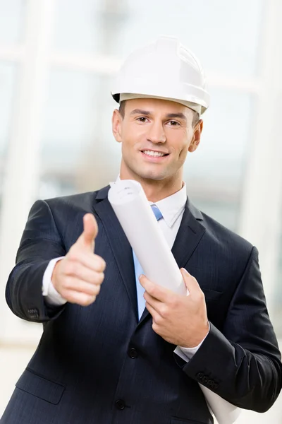 Engineer in hard hat hands blueprint and thumbs up — Stock Photo, Image