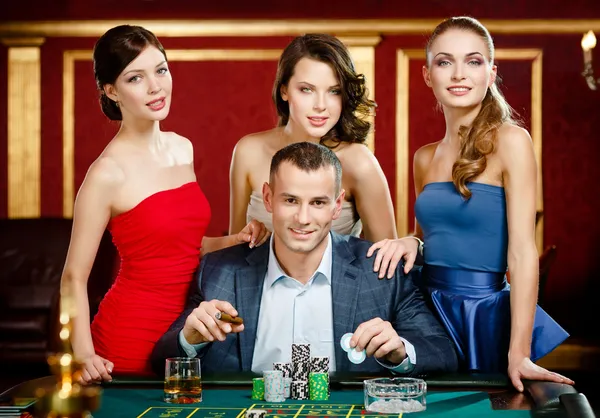 Mann von Damen umgeben spielt Roulette — Stockfoto