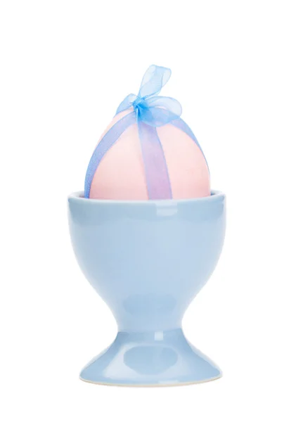 Colored easter egg with blue ribbon in egg cup — Stock Photo, Image