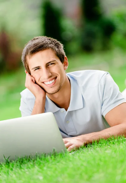 Mann liegt im Gras und arbeitet am Laptop — Stockfoto