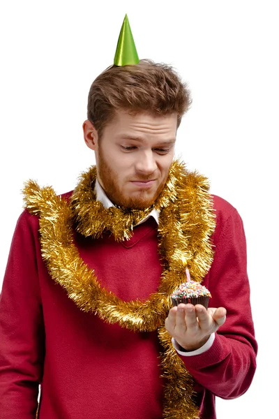 Enttäuschter Mann mit Lametta hält kleinen Kuchen — Stockfoto