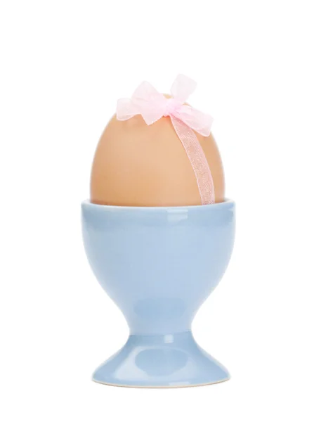 Colored easter egg with pink ribbon in egg cup — Stock Photo, Image