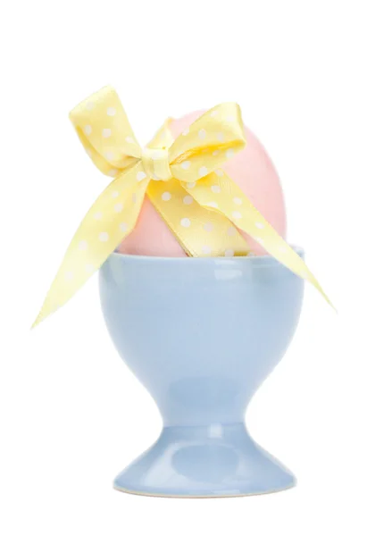 Colored easter egg with yellow ribbon in egg cup — Stock Photo, Image