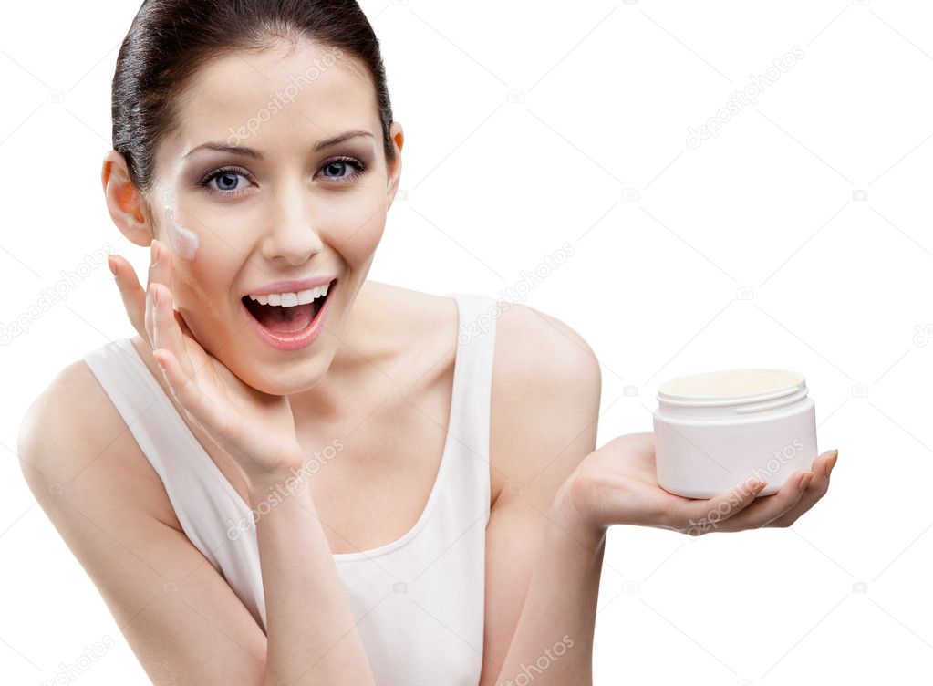 Woman putting on emollient cream from container on face