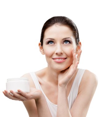 Woman applying moisture cream from container on face clipart