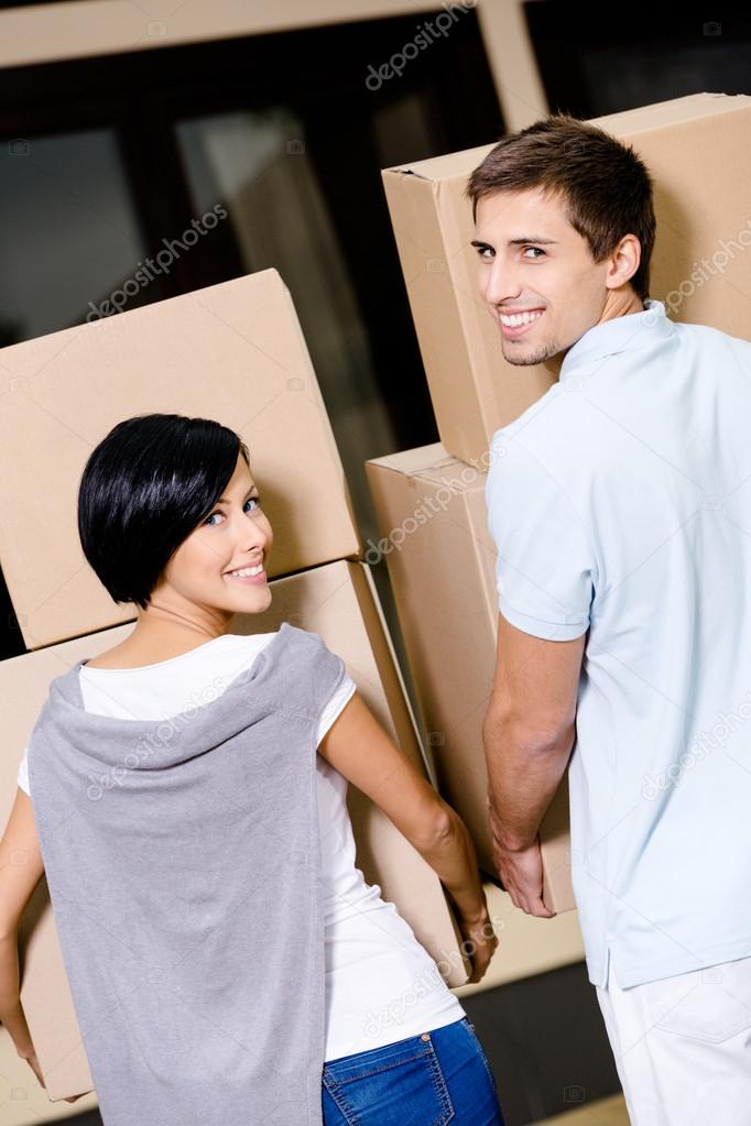 Back view of couple carrying cardboard boxes