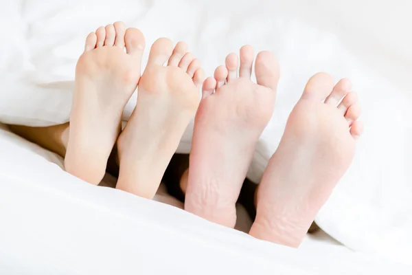 Primer plano de los pies de la pareja acostada en el dormitorio — Foto de Stock