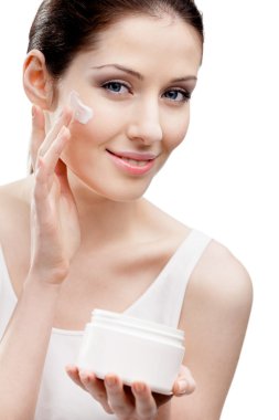 Woman applying lifting cream from container on face clipart