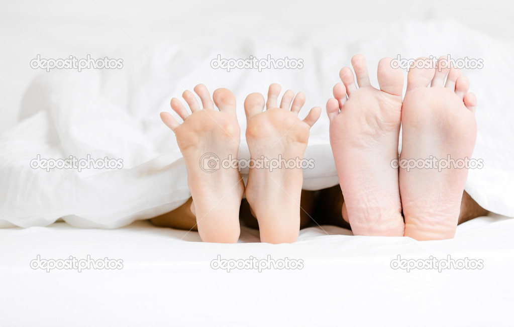 Close up view of feet of the couple lying in bed