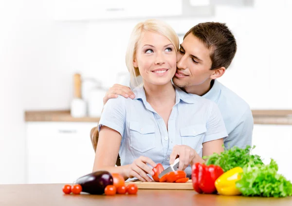 Homem beija menina enquanto ela está cozinhando — Fotografia de Stock