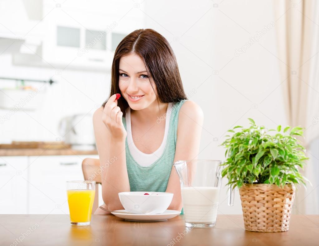 Woman eating strawberry with milk and orange juice