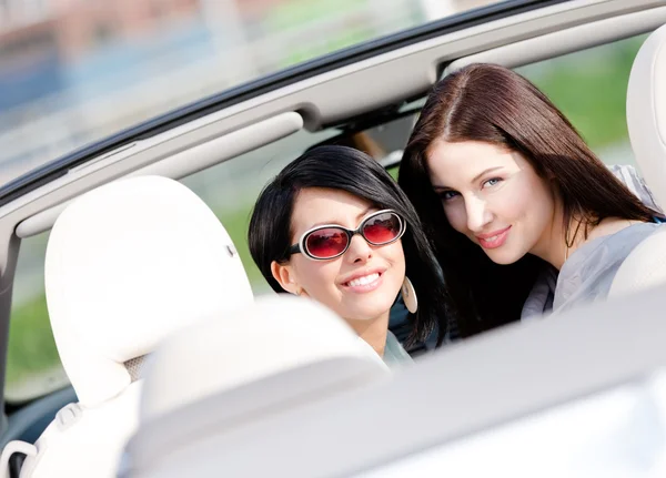 Två glada tjejer som sitter i cabriolet vända tillbaka — Stockfoto