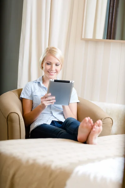 Girl sitting on the couch with silver pad — Stock Photo, Image