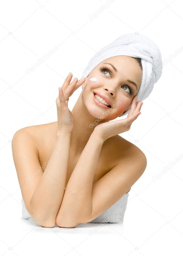 Pretty girl with towel on head applies cream on face