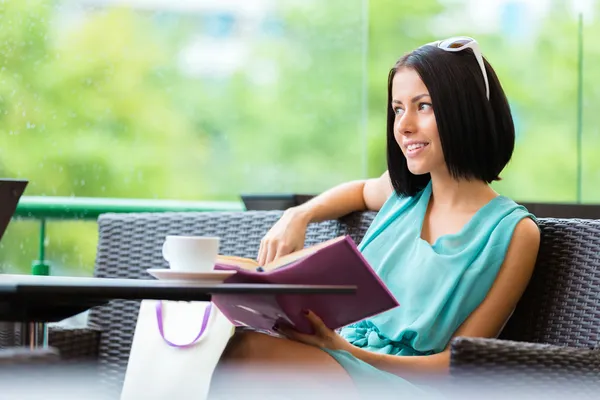 Girl reading book drinks tea at the bar — Stock Photo, Image