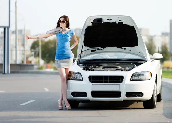 Женщина автостопом возле сломанной машины — стоковое фото