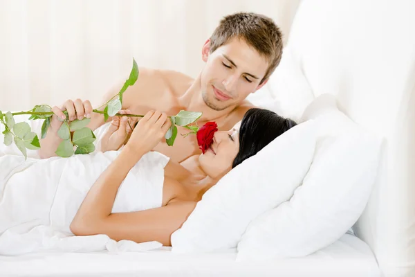 Mann im Bett liegend schenkt Mädchen rote Rose — Stockfoto