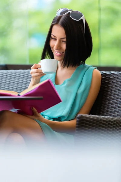 Girl reading book drinks tea at the cafe — Stock Photo, Image