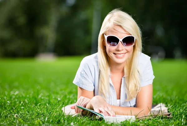 Female student reading book on the green grass — Stock Photo, Image