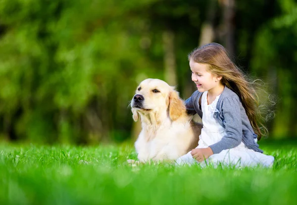 Niña sentada en la hierba con el perro — Foto de Stock