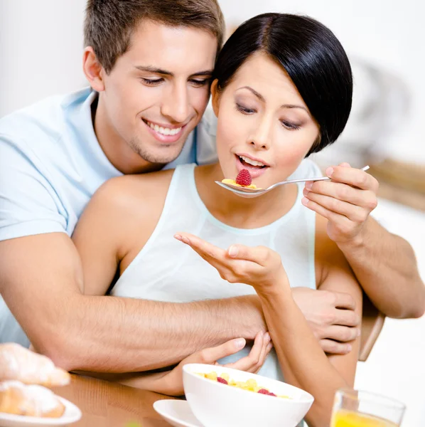 Young man feeds and embraces his girlfriend — Stock Photo, Image