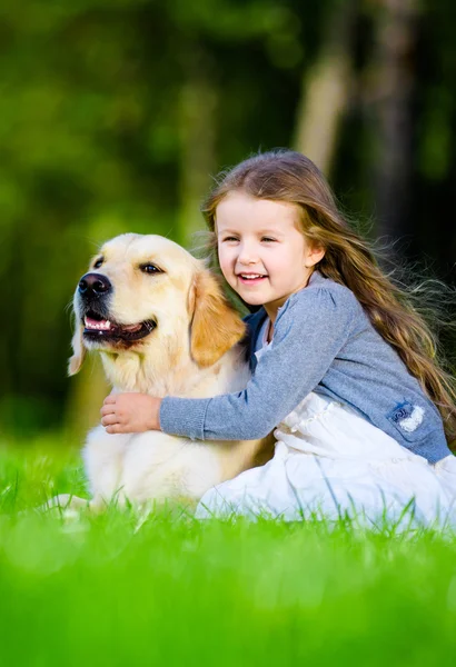 Little girl sitting on the grass with labrador — Stock Photo, Image