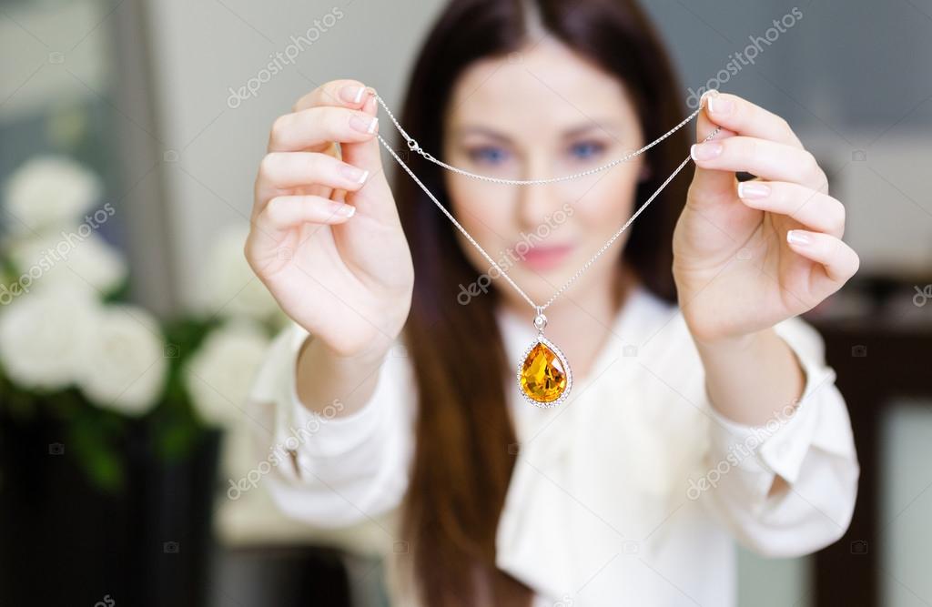 Woman keeping necklace with yellow sapphire