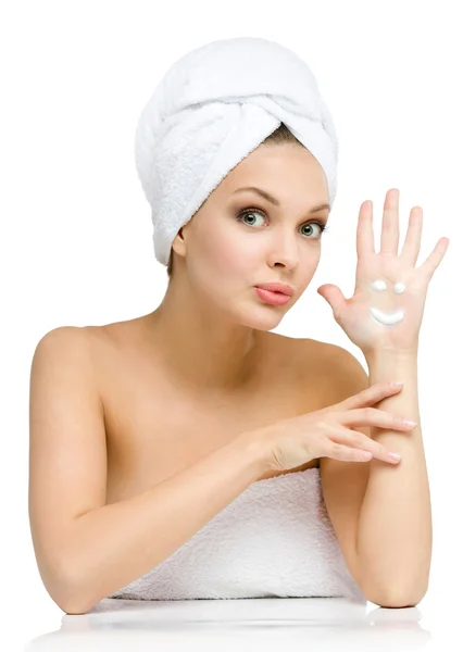 Woman with towel on head shows cream smiley on palm — Stock Photo, Image