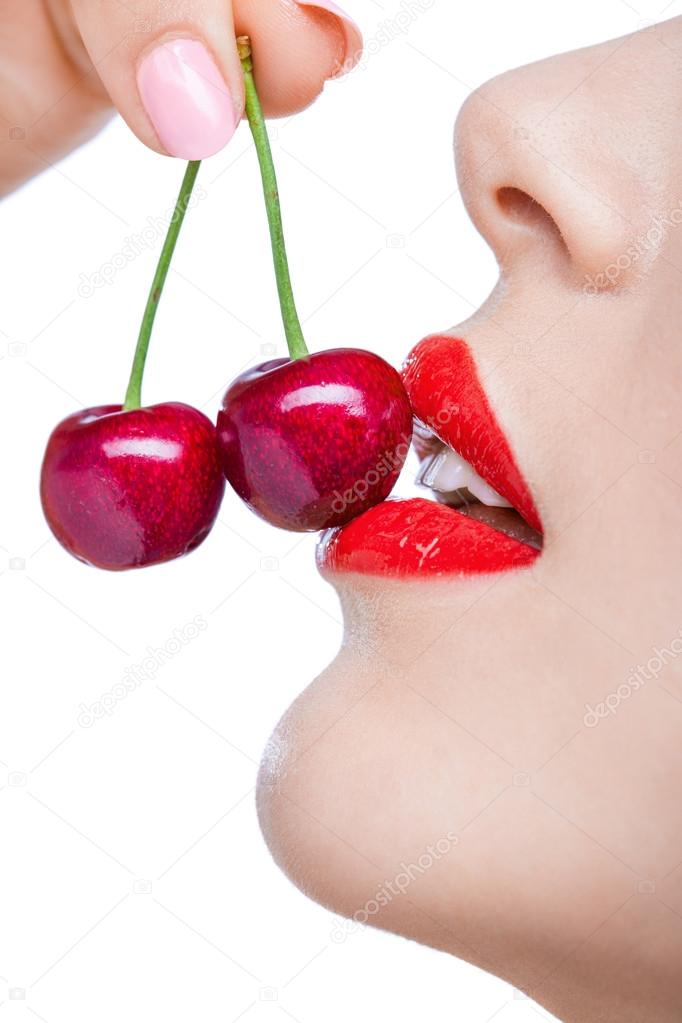 Woman with red lips eating two berries