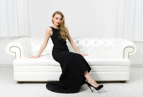 Woman sitting on white leather sofa — Stock Photo, Image