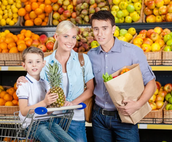 Familjen mot hyllor av frukter har shopping — Stockfoto