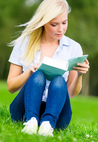 Frau, die Buch liest, sitzt im Gras — Stockfoto