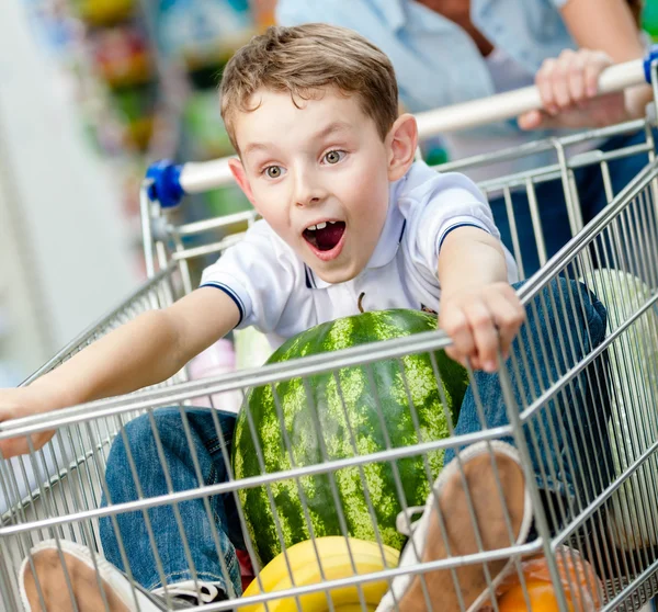 Chlapec sedí v nákupním vozíku — Stock fotografie