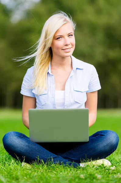 Vrouwelijke student met laptop zittend op het gras — Stockfoto